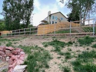 A wooden fence is sitting on top of a grassy hill next to a house.