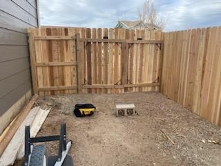 A wooden fence is being built in the backyard of a house.
