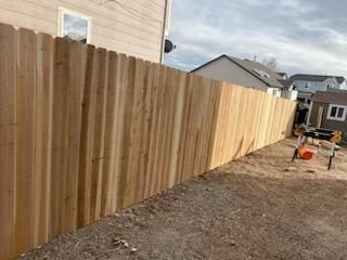 A wooden fence is being built in the backyard of a house.