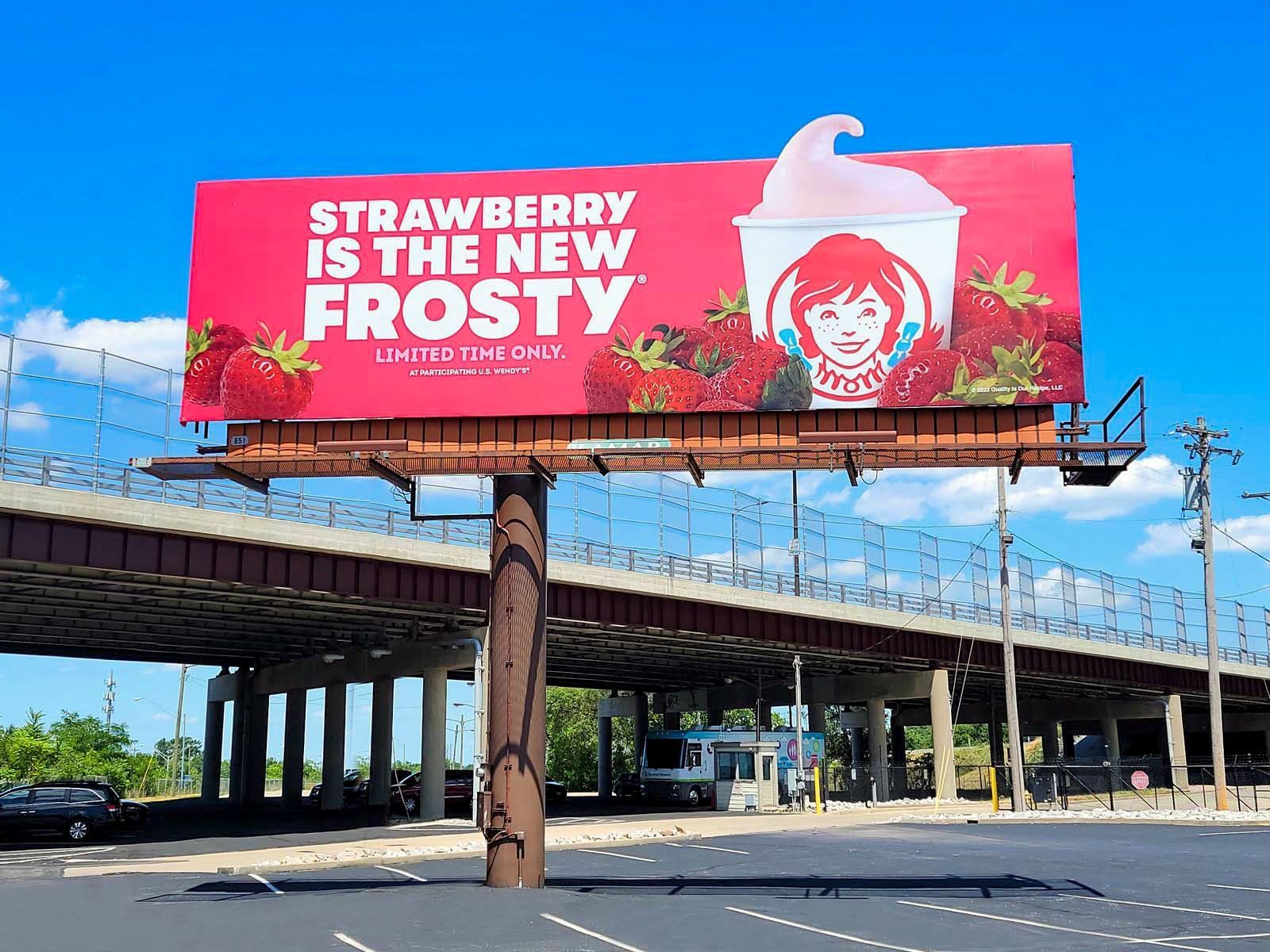 A billboard for wendy 's says strawberry is the new frosty.