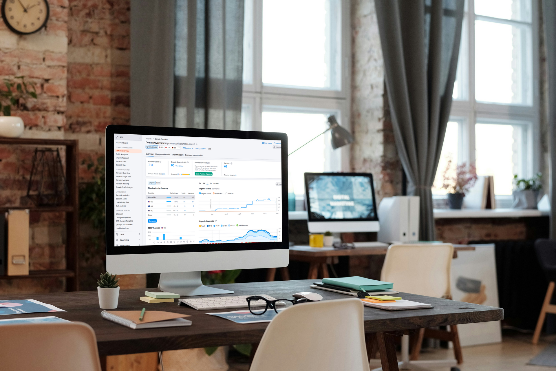 A computer monitor is sitting on top of a wooden desk in an office.