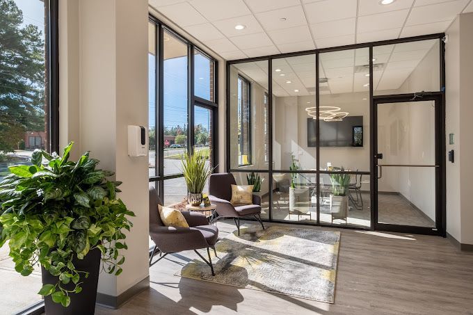 A living room with a lot of windows and chairs.