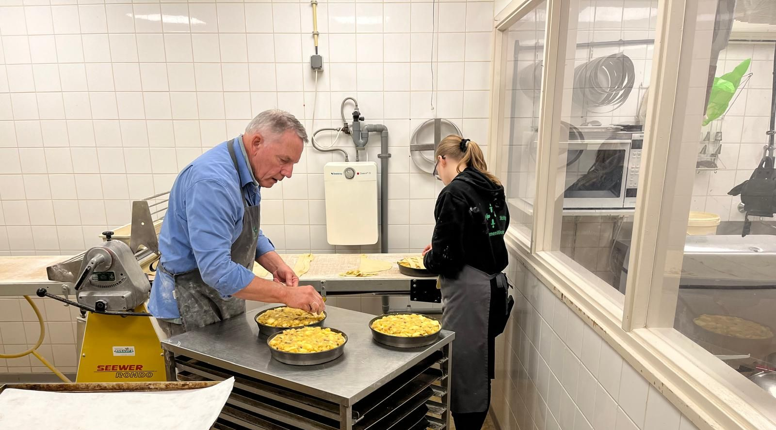 Bakker en deelnemer maken samen appeltaart.