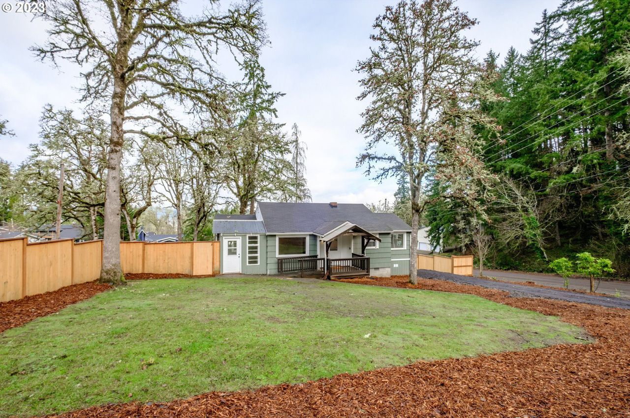 A house with a wooden fence and a large lawn in front of it.