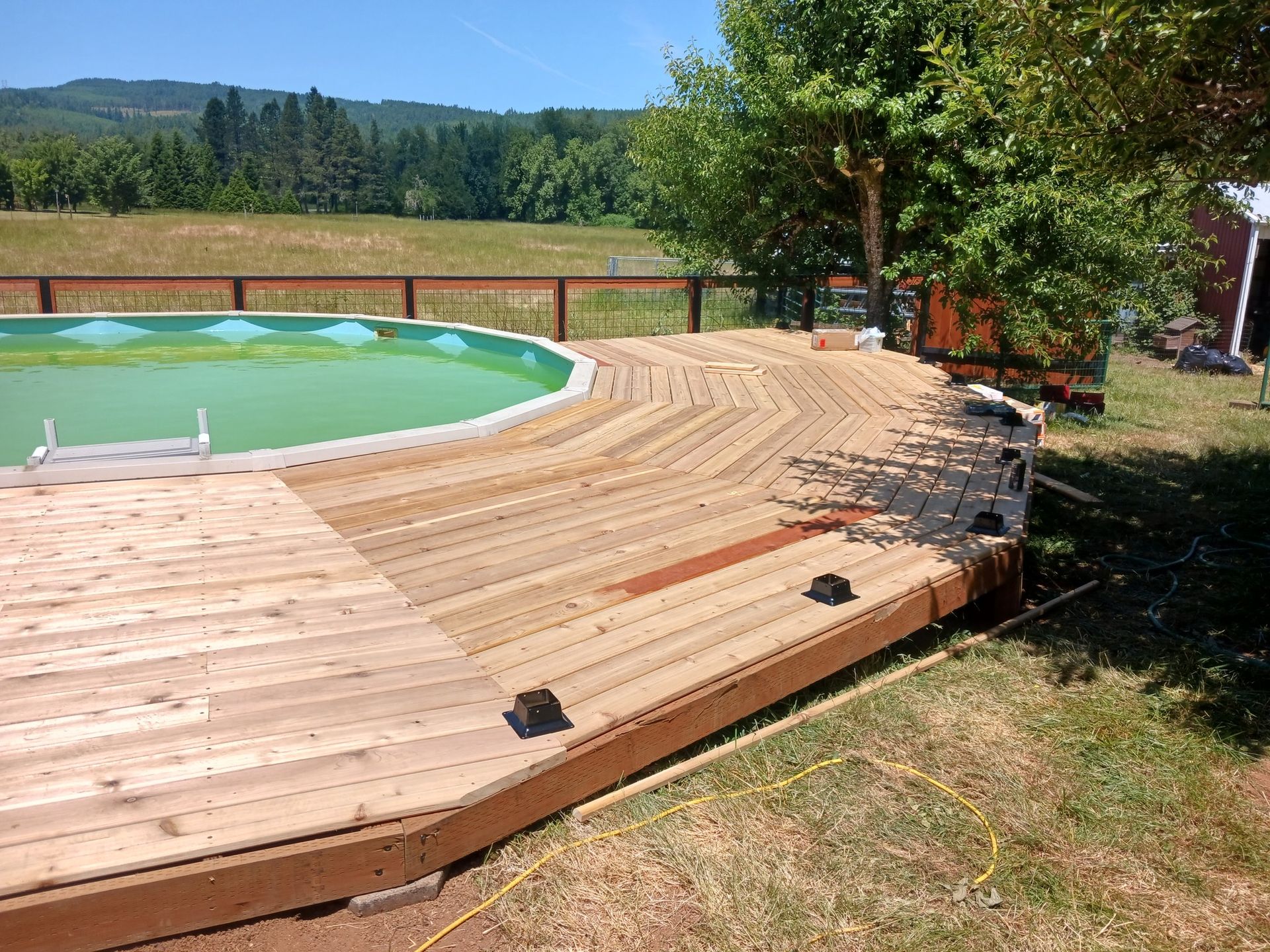 A wooden deck with a swimming pool in the background