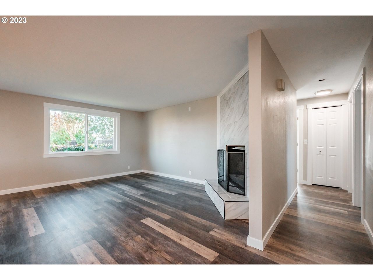 An empty living room with hardwood floors and a fireplace.