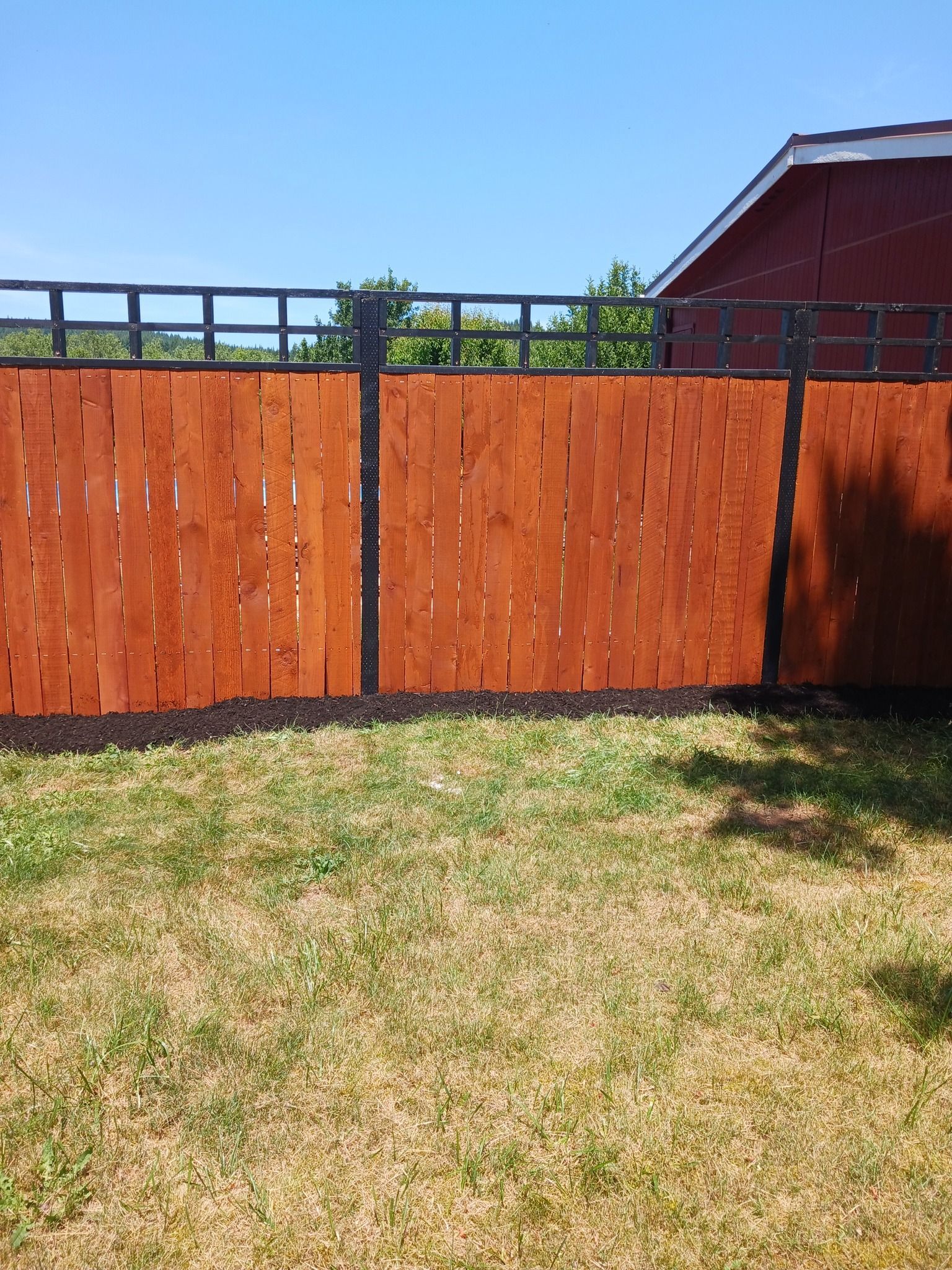 A wooden fence is in the middle of a lush green yard.