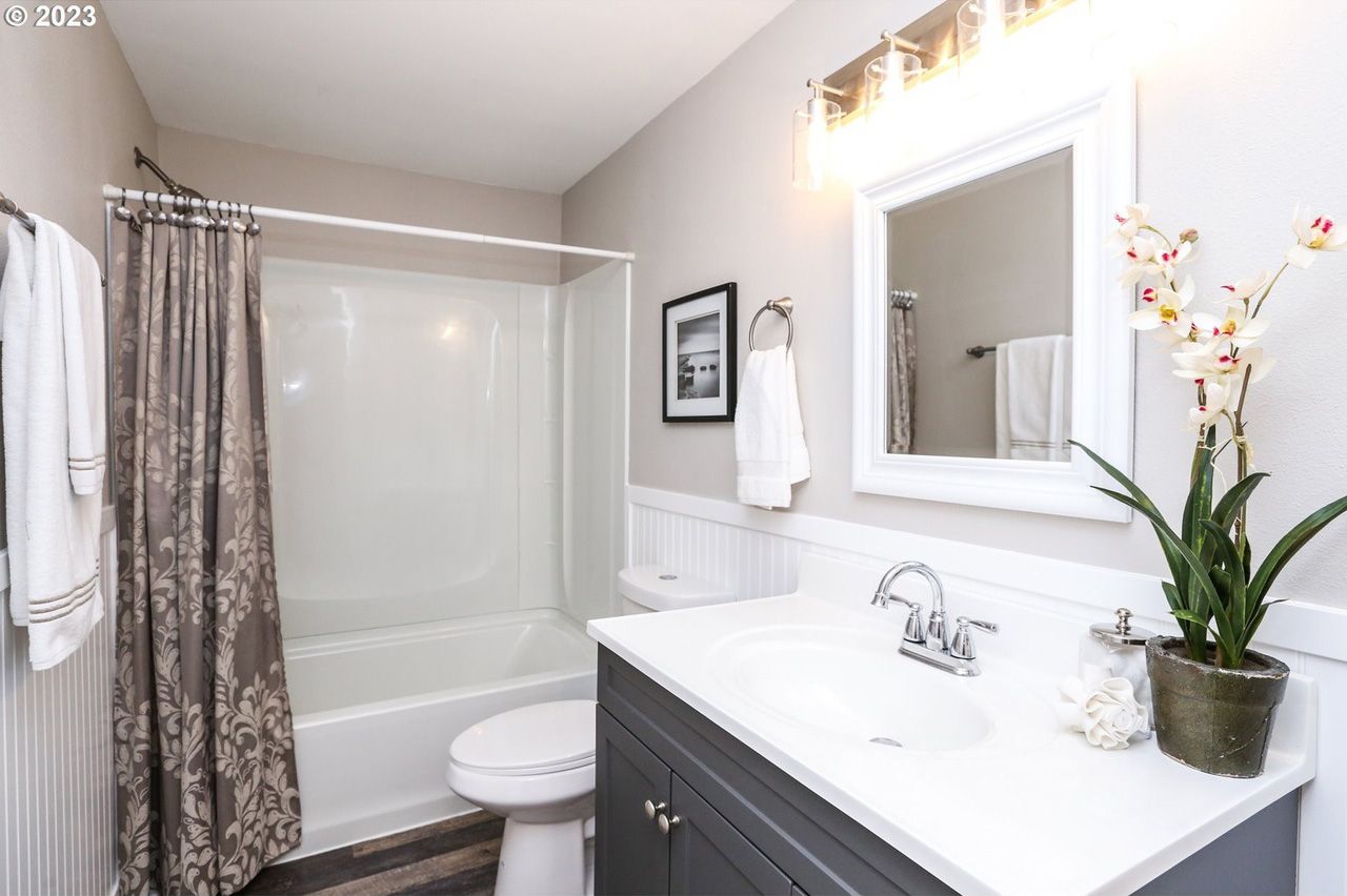A bathroom with a sink , toilet , shower and mirror.