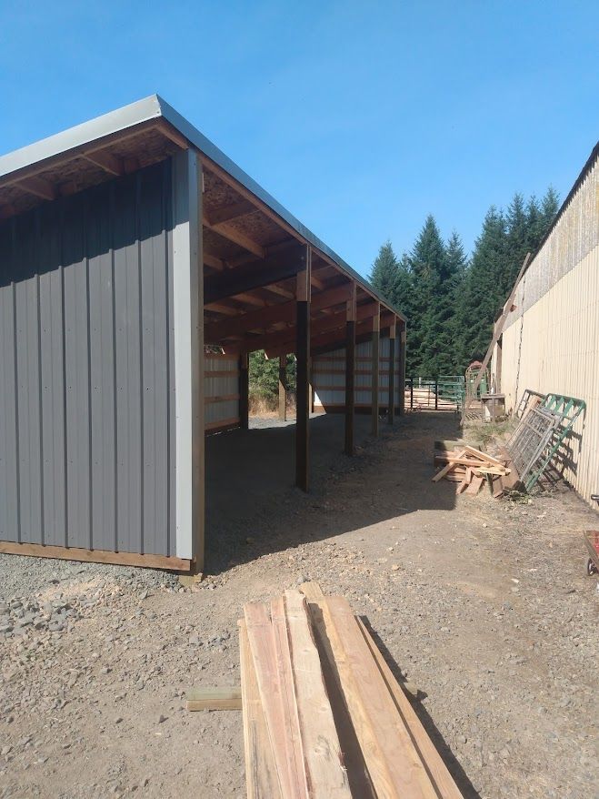 A shed with a wooden roof is sitting in a dirt field.
