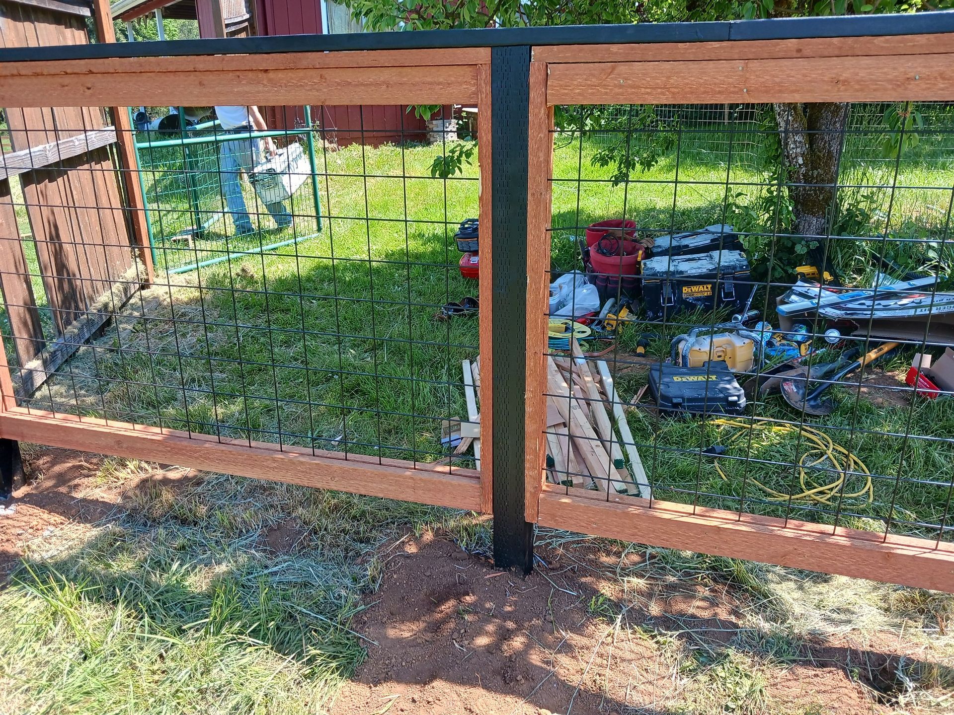A wooden fence is being built in a backyard.