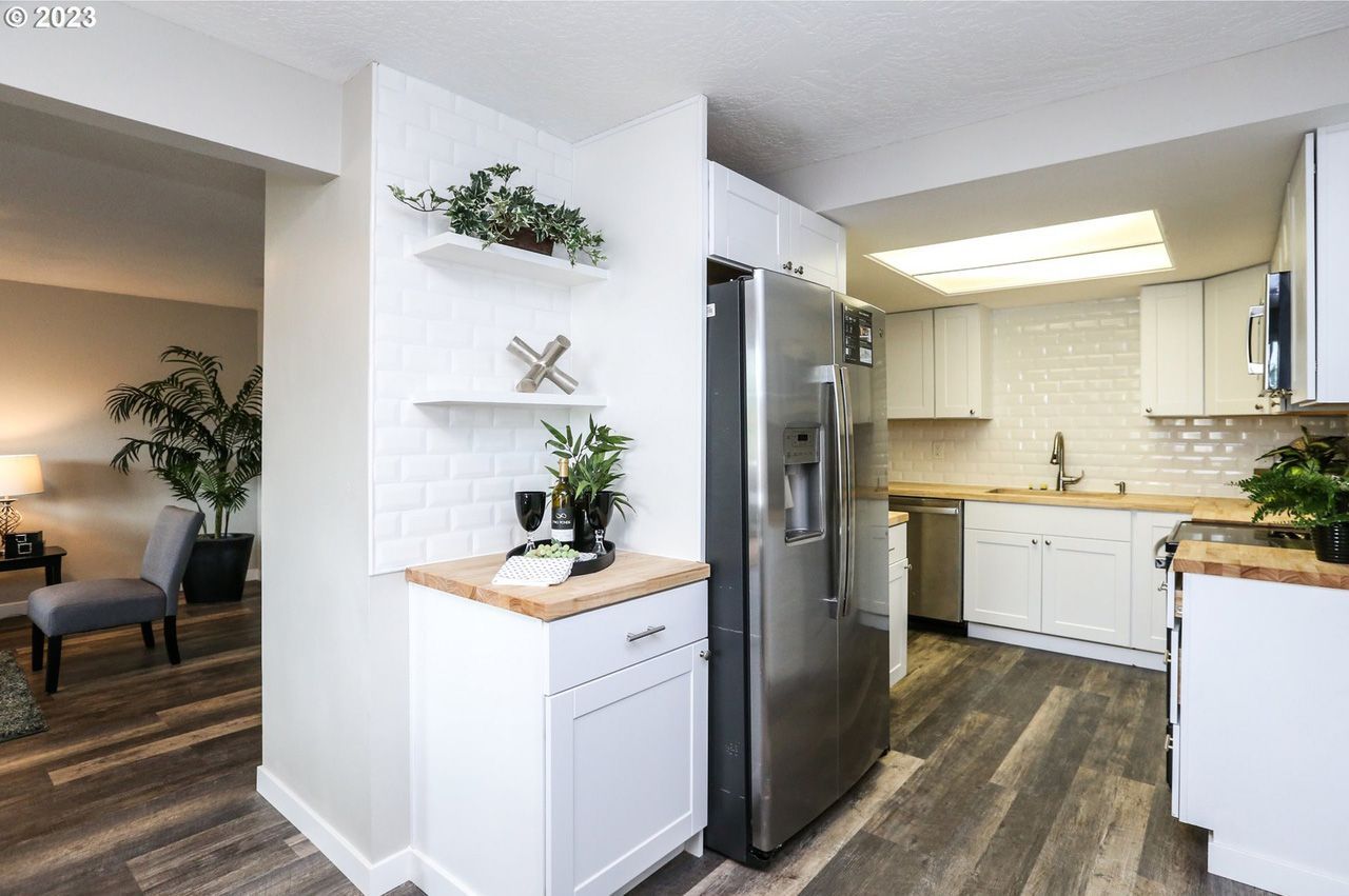 A kitchen with white cabinets and a stainless steel refrigerator.
