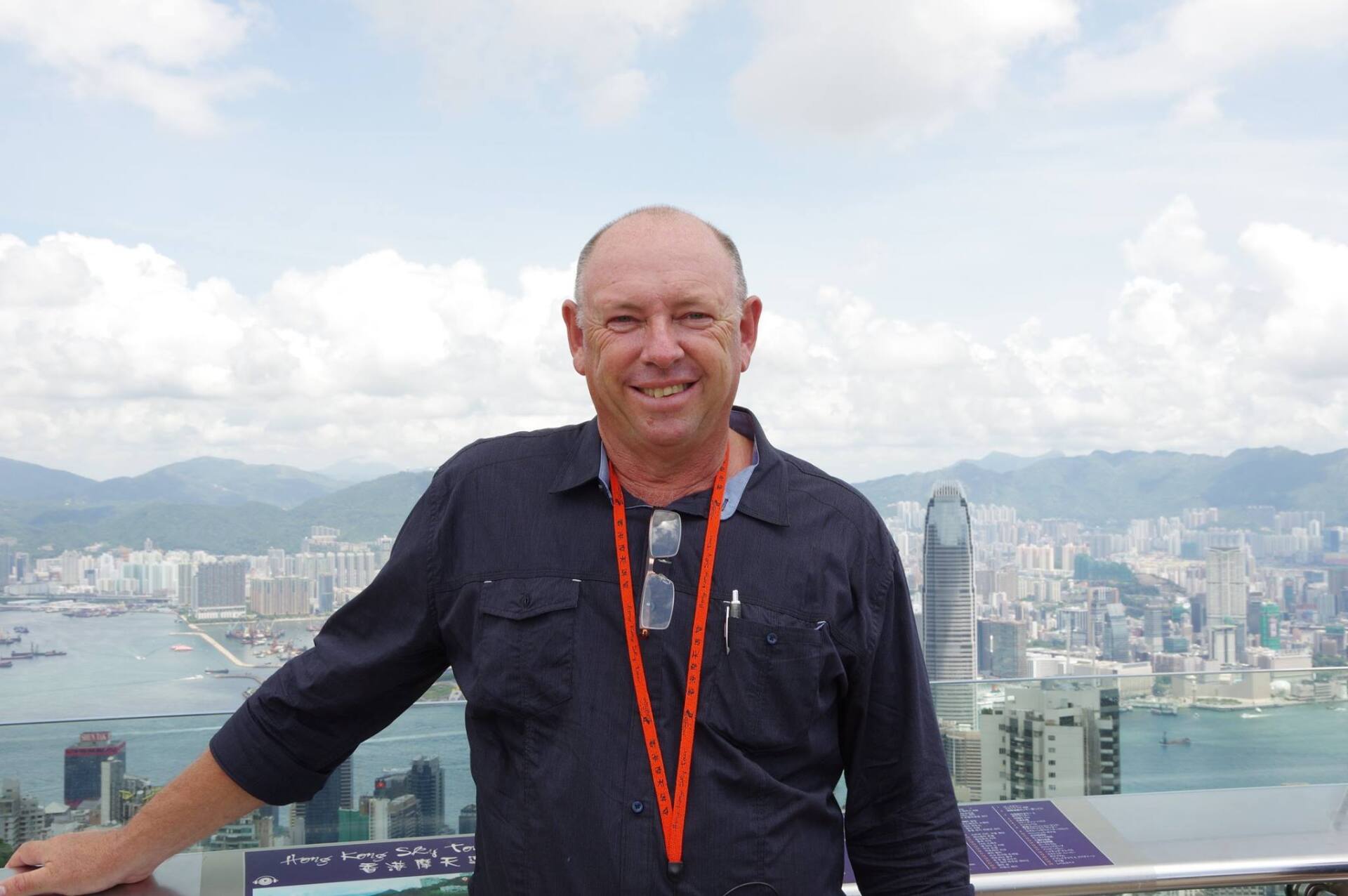 A man is standing on a balcony overlooking a city.