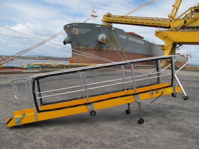 A large ship is docked next to a yellow crane