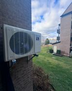 Un climatiseur blanc est monté sur le côté d'un bâtiment en briques.