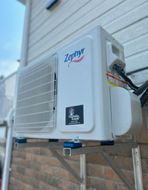 Un climatiseur blanc est monté sur le côté d'une maison.