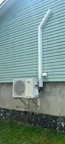 Un climatiseur blanc est monté sur le côté d'une maison.