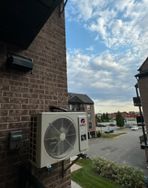 Un grand climatiseur est monté sur le côté d'un bâtiment en briques.