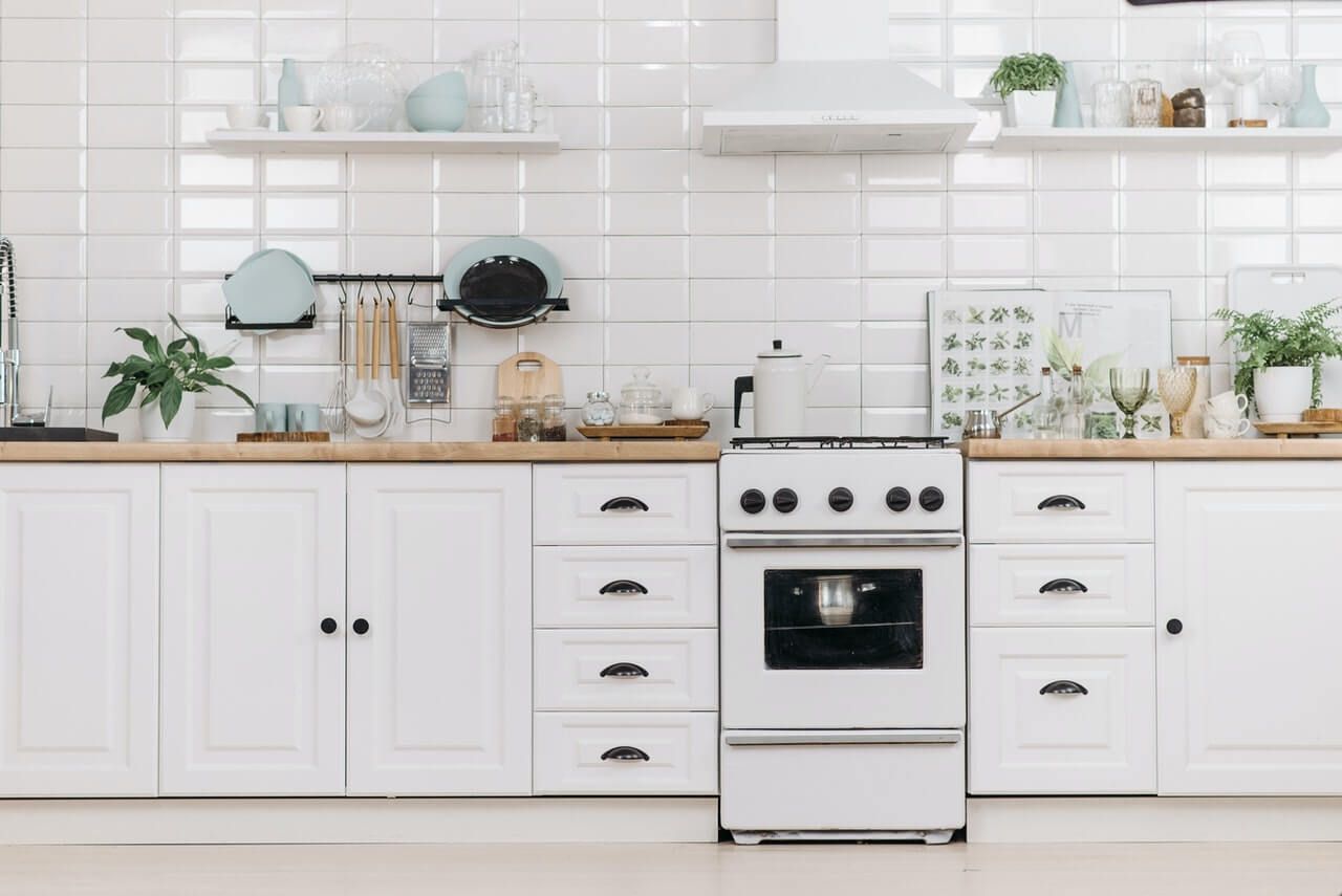 Close up of artsy white kitchen with pulls on drawers and knobs on cabinets