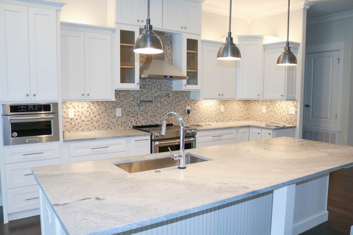 Modern white refinished kitchen cabinets paired with silvery granite countertops.