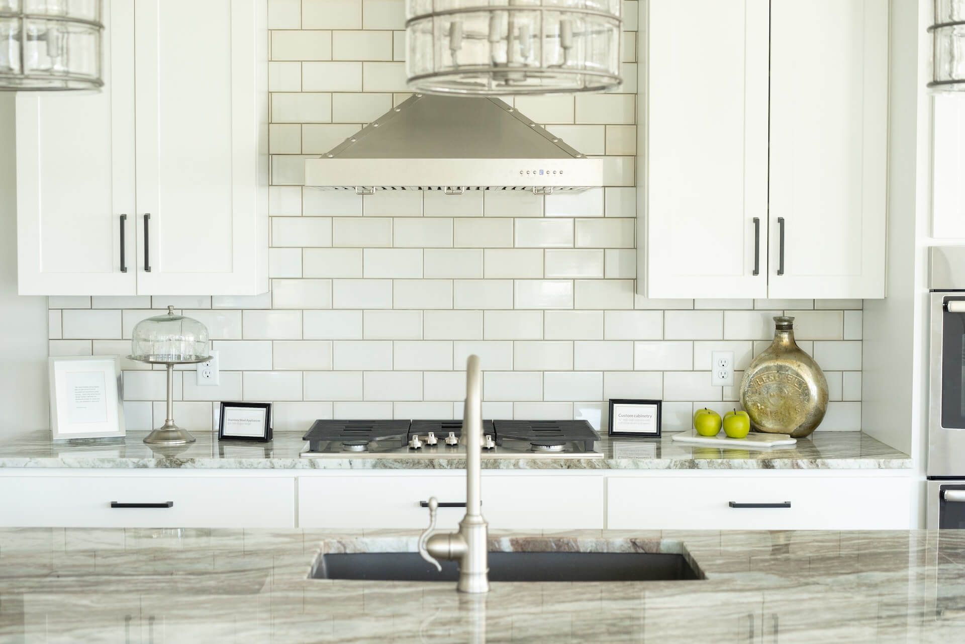 Close-up of a remodeled kitchen with white cabinets, black hardware, and stainless steel appliances