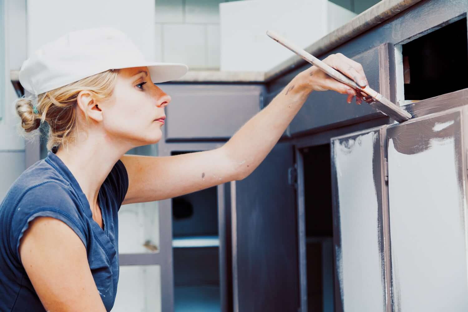 Woman painting her kitchen cabinets herself