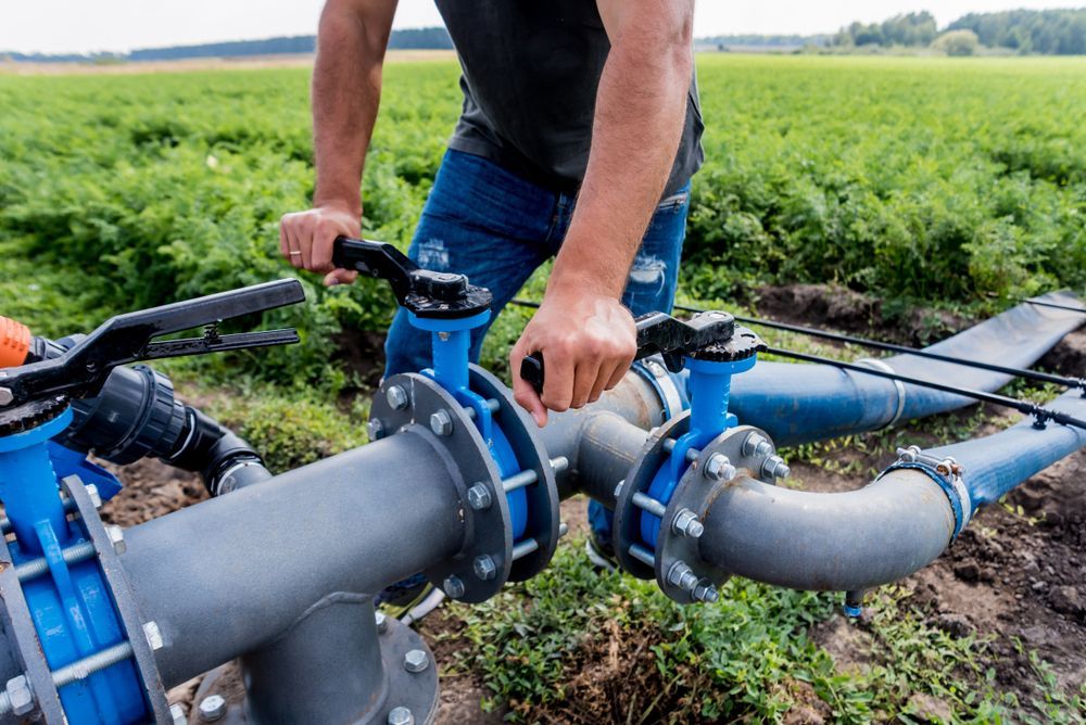 A Man Is Working On A Water Pump In A Field — Blackpoly Pipelines in Forbes, NSW