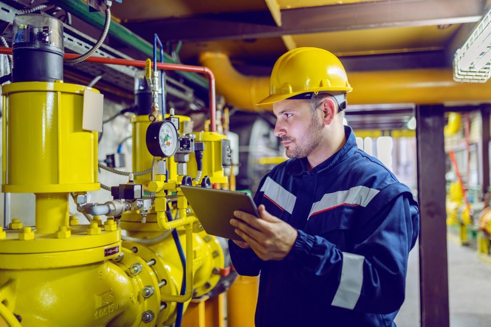 A Man In A Hard Hat Is Looking At A Clipboard In A Factory — Blackpoly Pipelines in Forbes, NSW