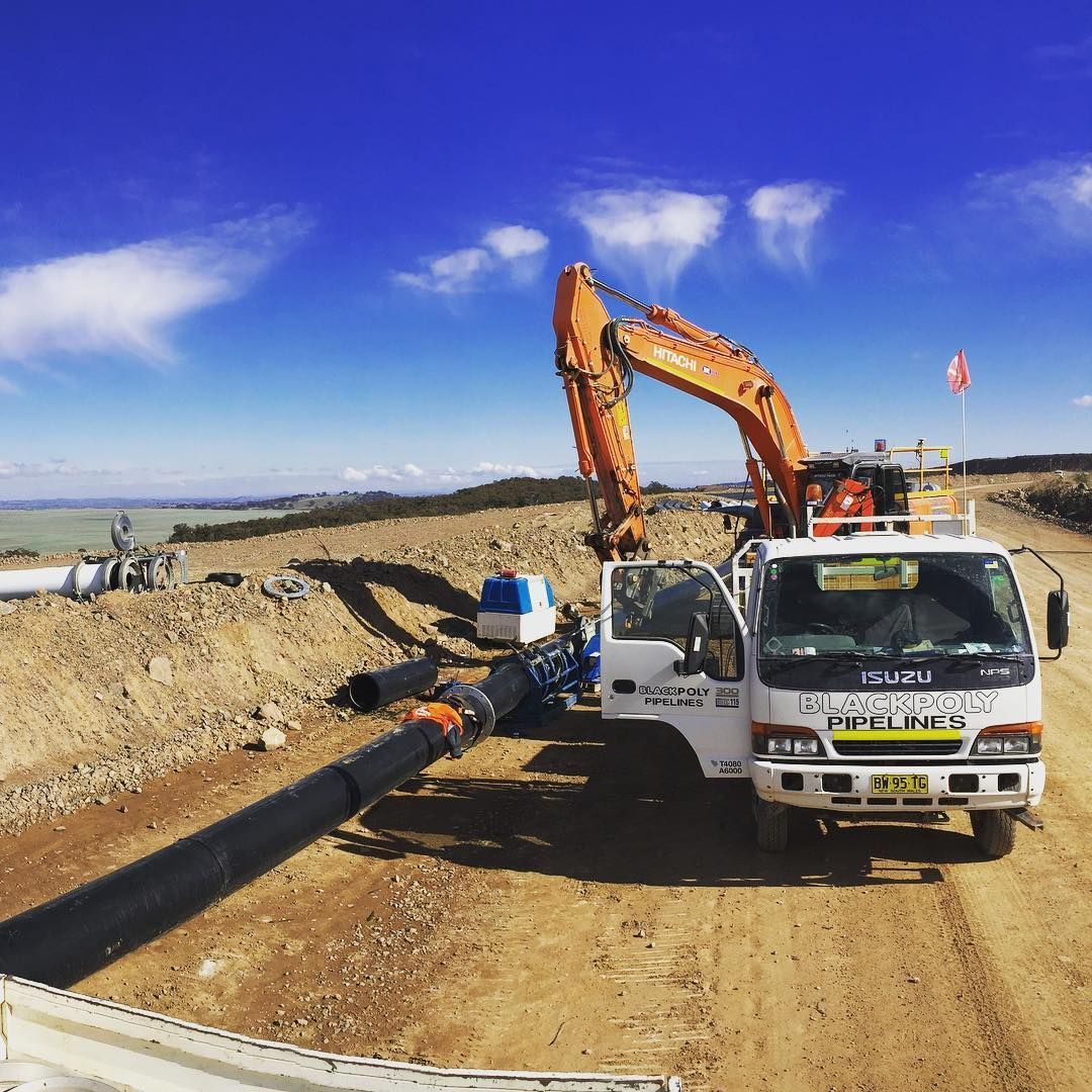 A Truck Is Parked On The Side Of A Dirt Road Next To An Excavator — Blackpoly Pipelines in Orange, NSW