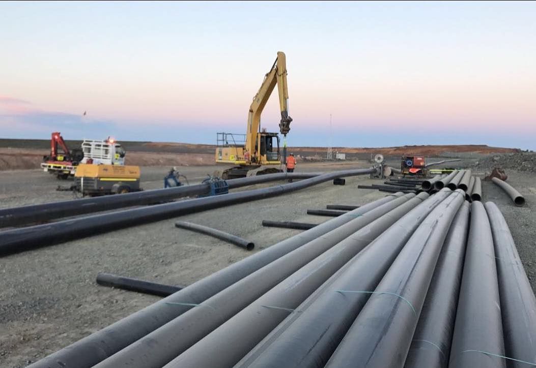 A Construction Site With A Lot Of Pipes And A Yellow Excavator — Blackpoly Pipelines in Orange, NSW