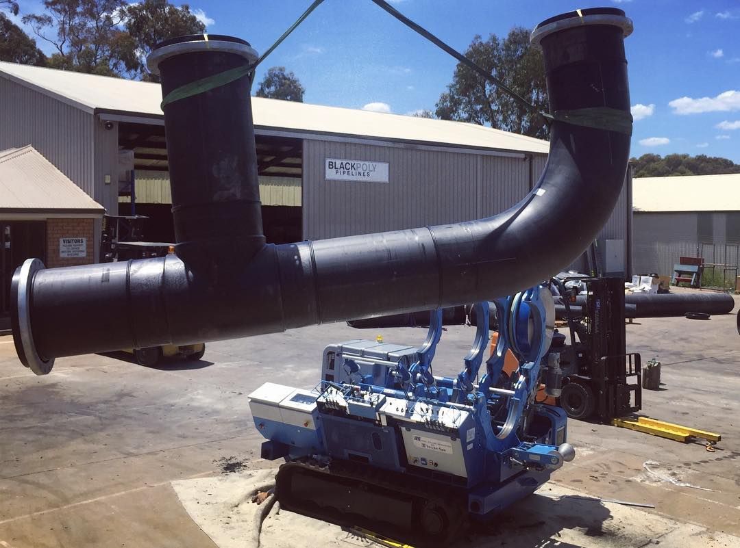 A Large Pipe Is Being Lifted By A Crane In Front Of A Building — Blackpoly Pipelines in Orange, NSW