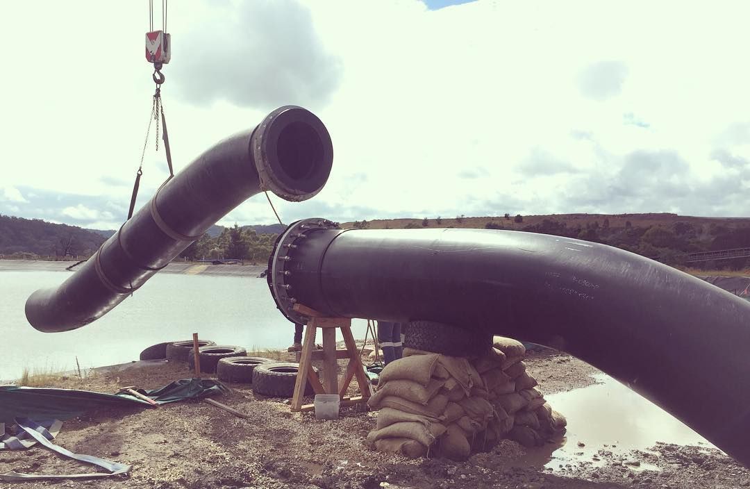 A Crane Is Lifting A Large Pipe Over A Body Of Water — Blackpoly Pipelines in Orange, NSW