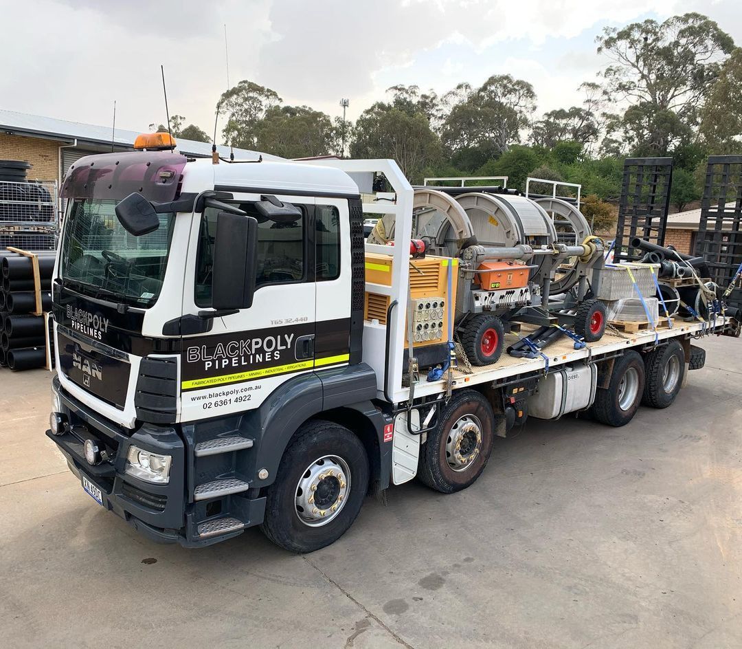 A Large Truck With A Flatbed Is Parked In A Parking Lot — Blackpoly Pipelines in Lithgow, NSW