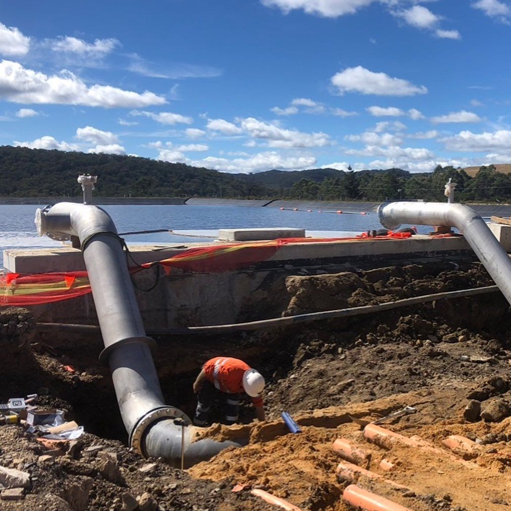 A Man Is Digging In The Dirt Near A Body Of Water — Blackpoly Pipelines in Orange, NSW