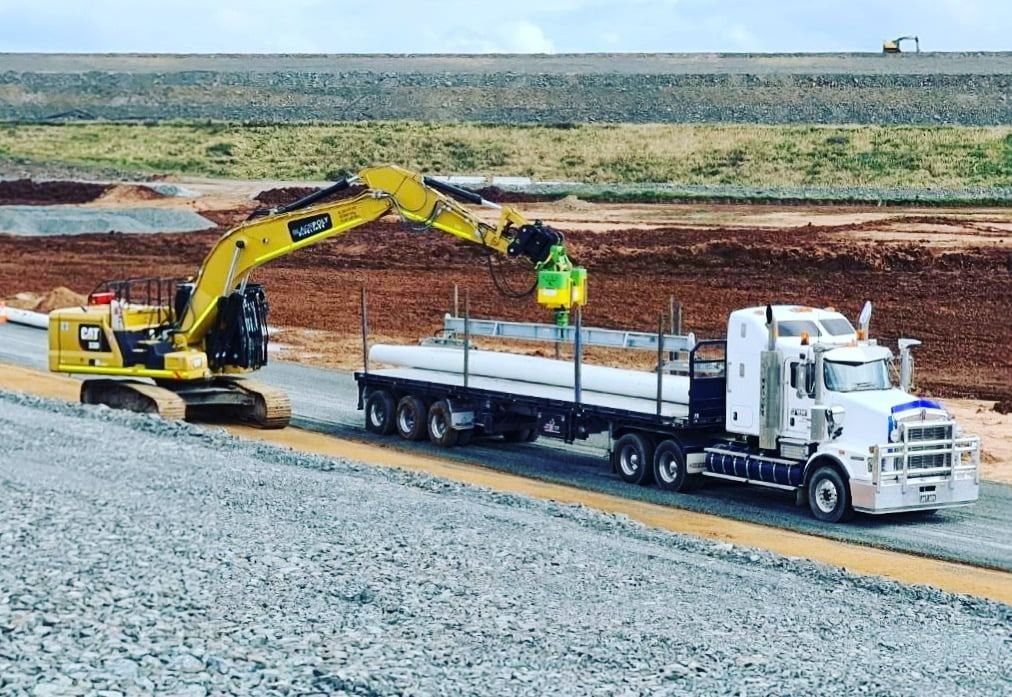 A Truck Is Being Towed By An Excavator On A Gravel Road — Blackpoly Pipelines in Orange, NSW