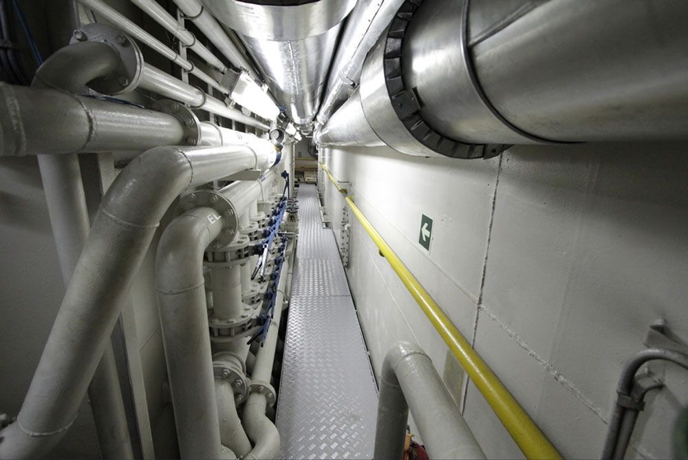 A Long Hallway Filled With Pipes And A Green Exit Sign — Blackpoly Pipelines in Mudgee, NSW