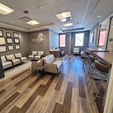 A long waiting room with wooden floors and chairs.