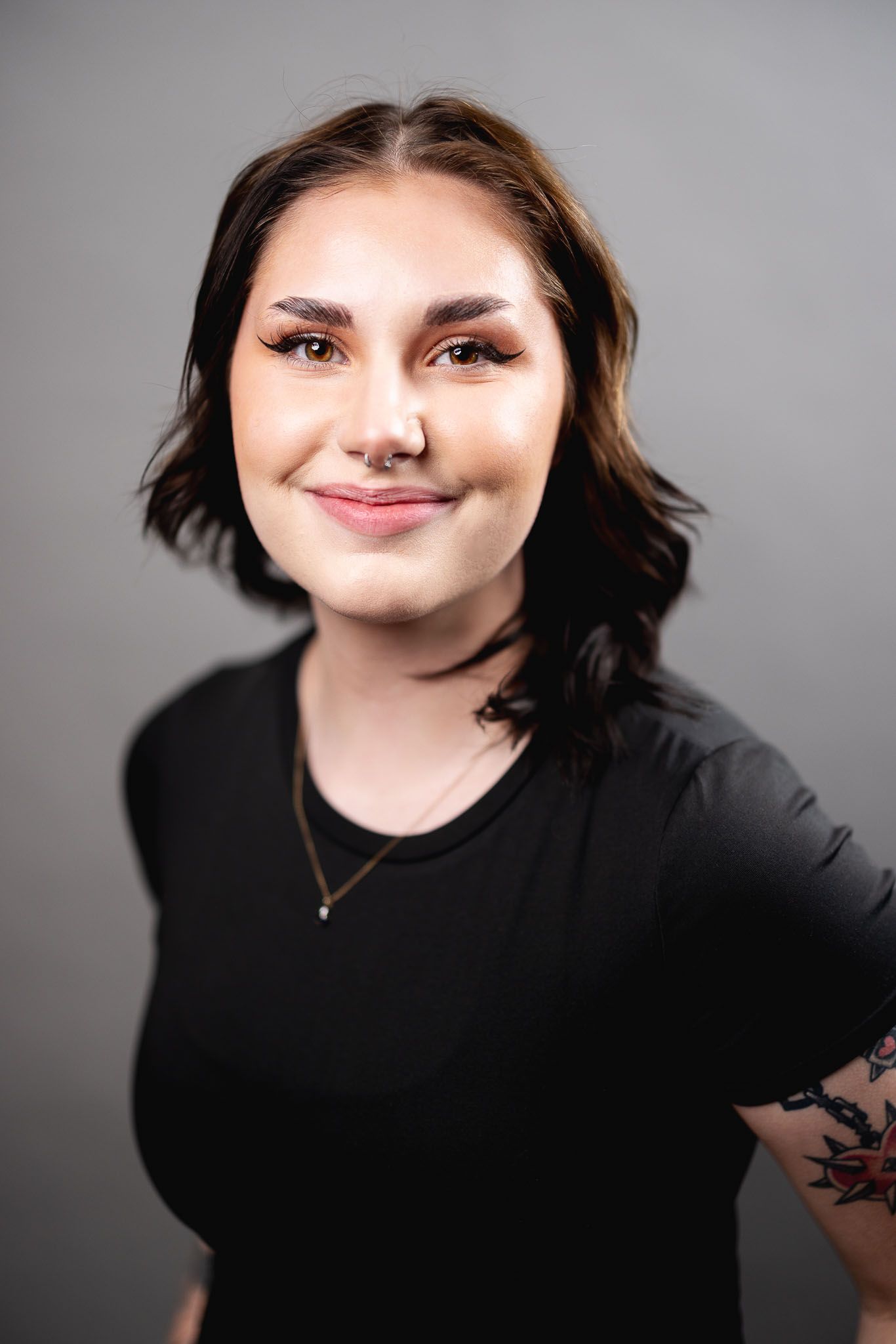 The woman is wearing a black shirt and has a tattoo on her arm.