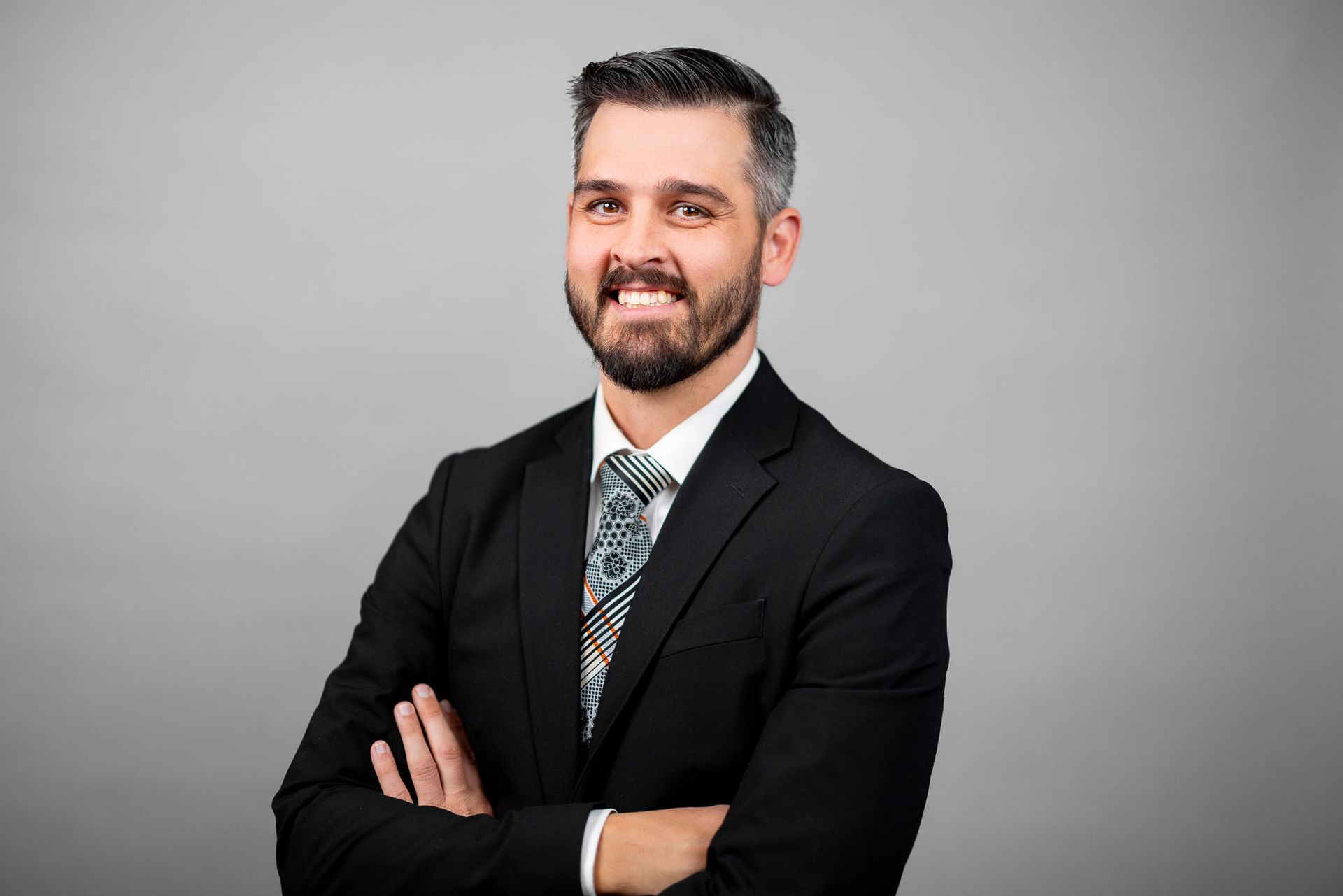 A man in a suit and tie is standing with his arms crossed.