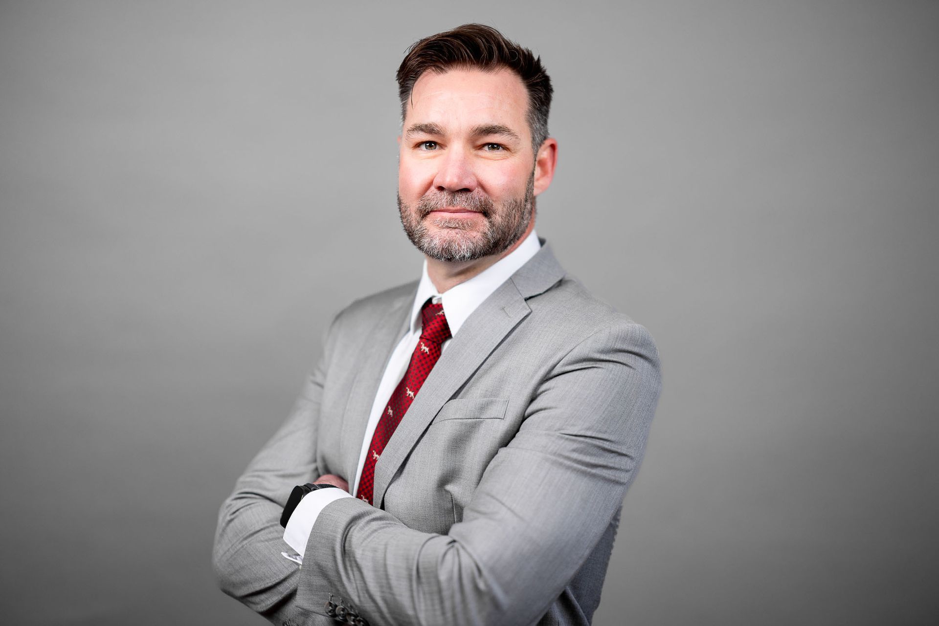 A man in a suit and tie is standing with his arms crossed.