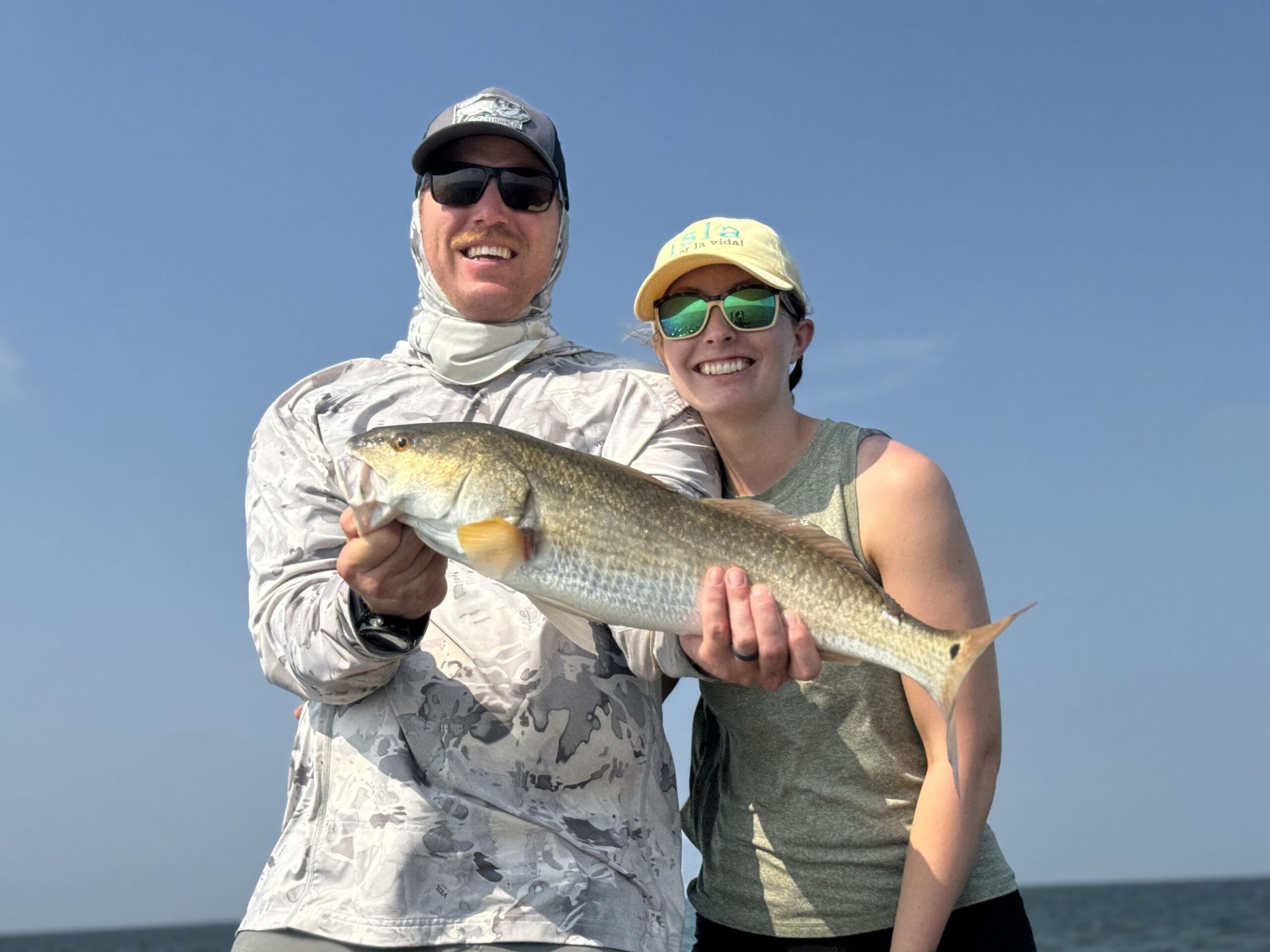 A man and a woman are holding a large fish in their hands.