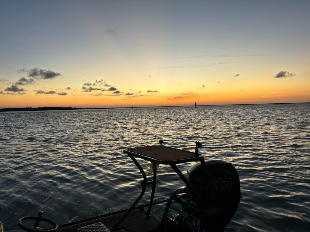 A boat is floating on top of a body of water at sunset.