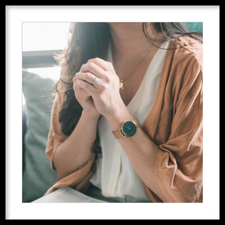 a woman wearing a watch and a necklace is praying