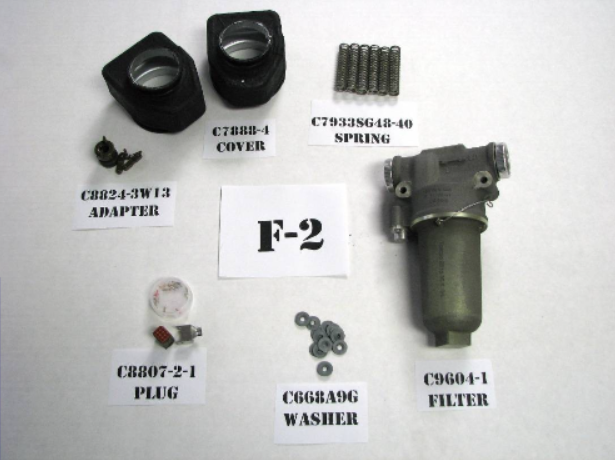 Components of an F-2 filter assembly, including a cover, springs, adapter, plug, washers, and filter.