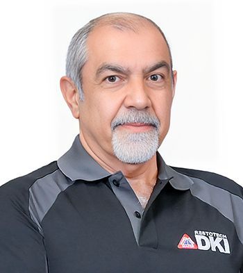 Man with graying hair and beard in gray polo shirt; logo visible.