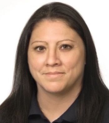 Woman with long dark hair, wearing a dark top, looking at the camera. Neutral expression. Studio background.