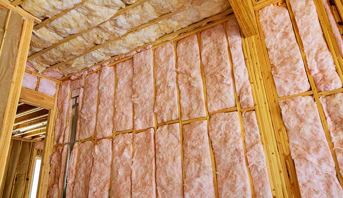 Interior house framing with pink fiberglass insulation installed.