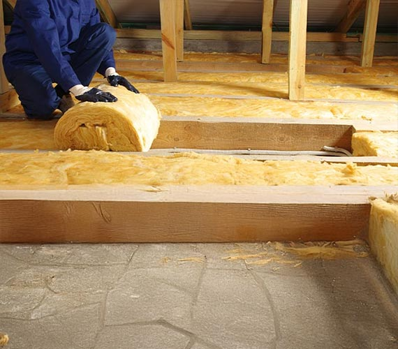 Person installing insulation in an attic.