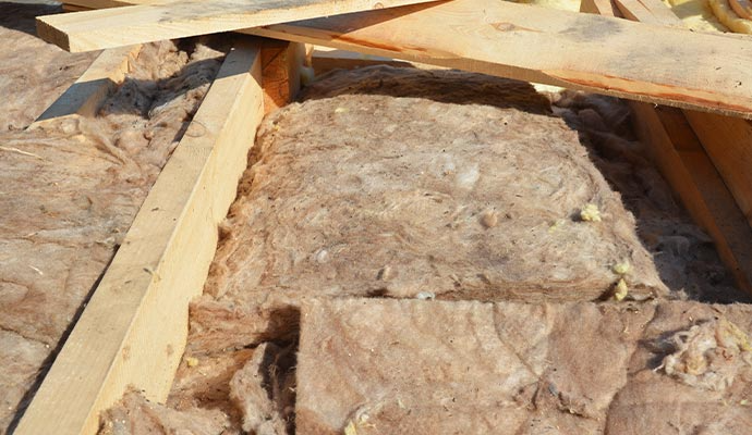 Close-up of roof insulation between wooden beams; light brown color.