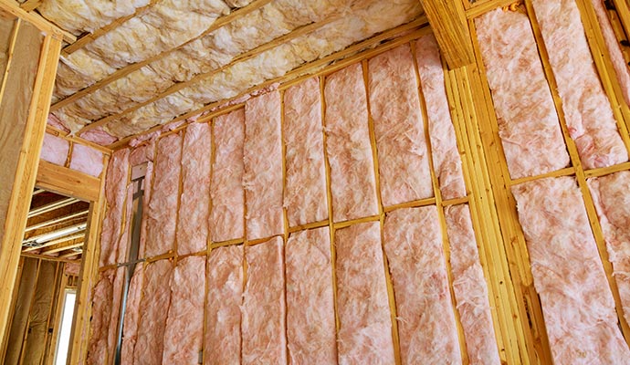 Pink insulation installed between wooden studs in a building under construction.