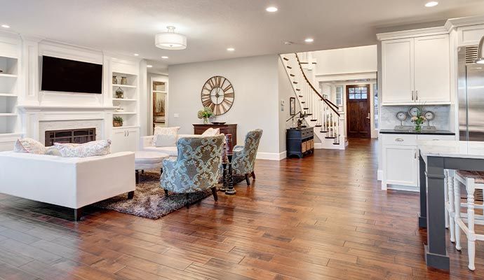 Bright, open-plan living space with white furnishings, wood floors, and a staircase leading upstairs.